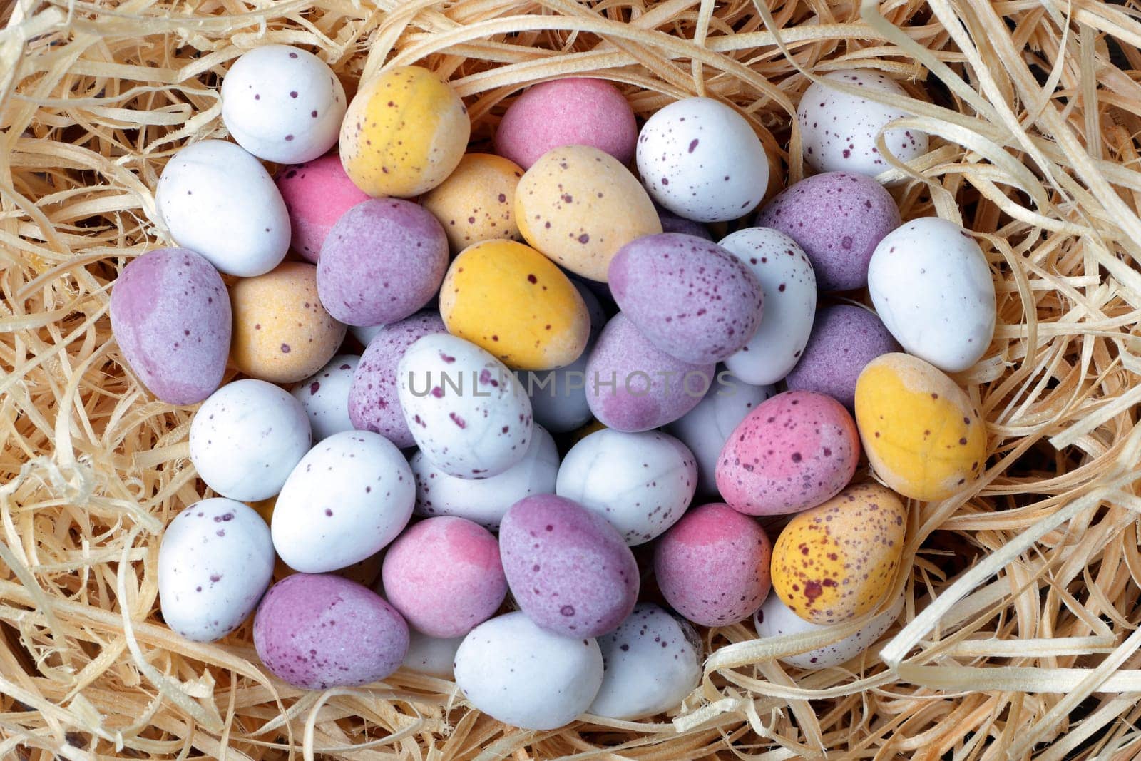 A cluth of Easter candy eggs on a straw background