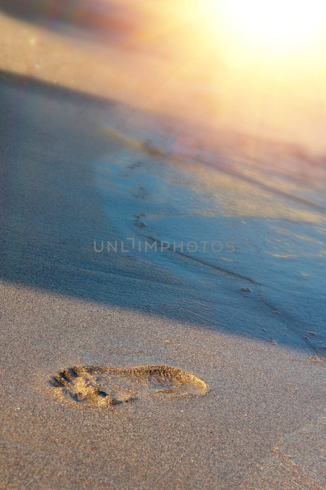 Greece, Rhodos - footprints on sand beach along the edge of sea. Kolympia