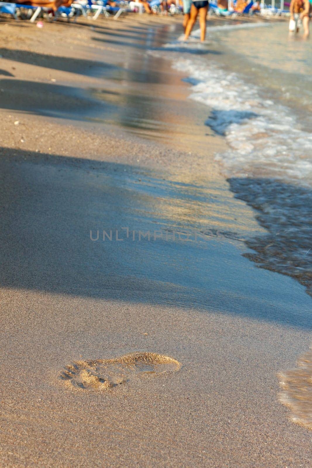 Greece, Rhodos - footprints on sand beach along the edge of sea. Kolympia