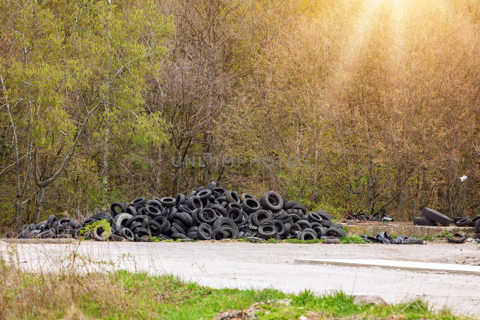 Illegal dump near the country road in the country on sunny day. Trash pollution in the nature. Dirty dump near the forest woods.