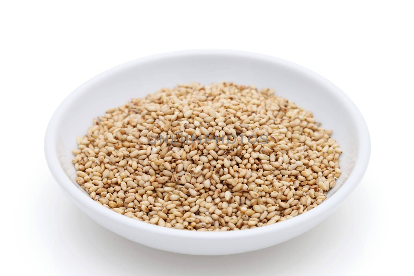 White sesame seeds in a dish on white background