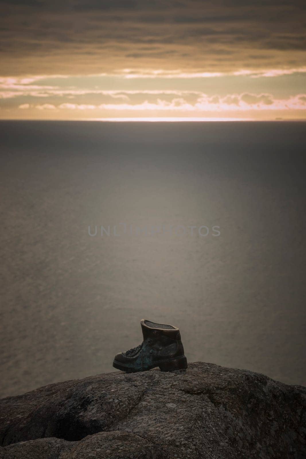 Sculpture of a bronze boot dedicated to the pilgrims of the Way of Saint James in Finisterre, Spain, at sunset