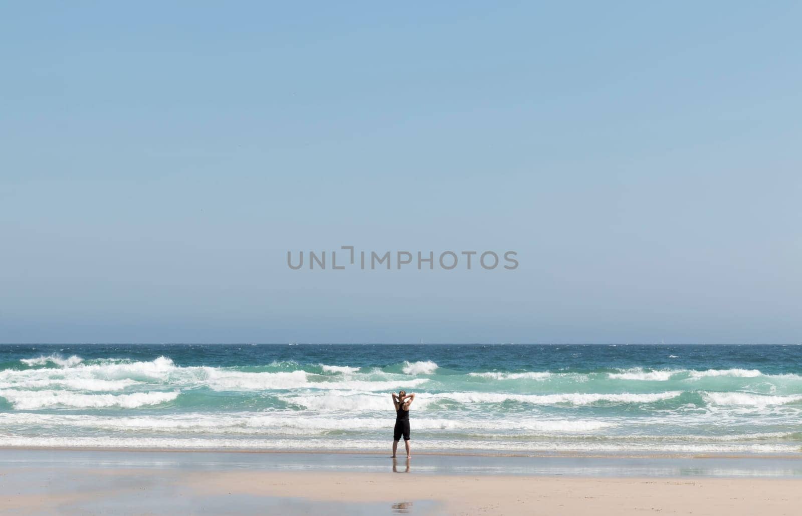 Relaxed blonde girl on her back contemplating the waves at the seashore