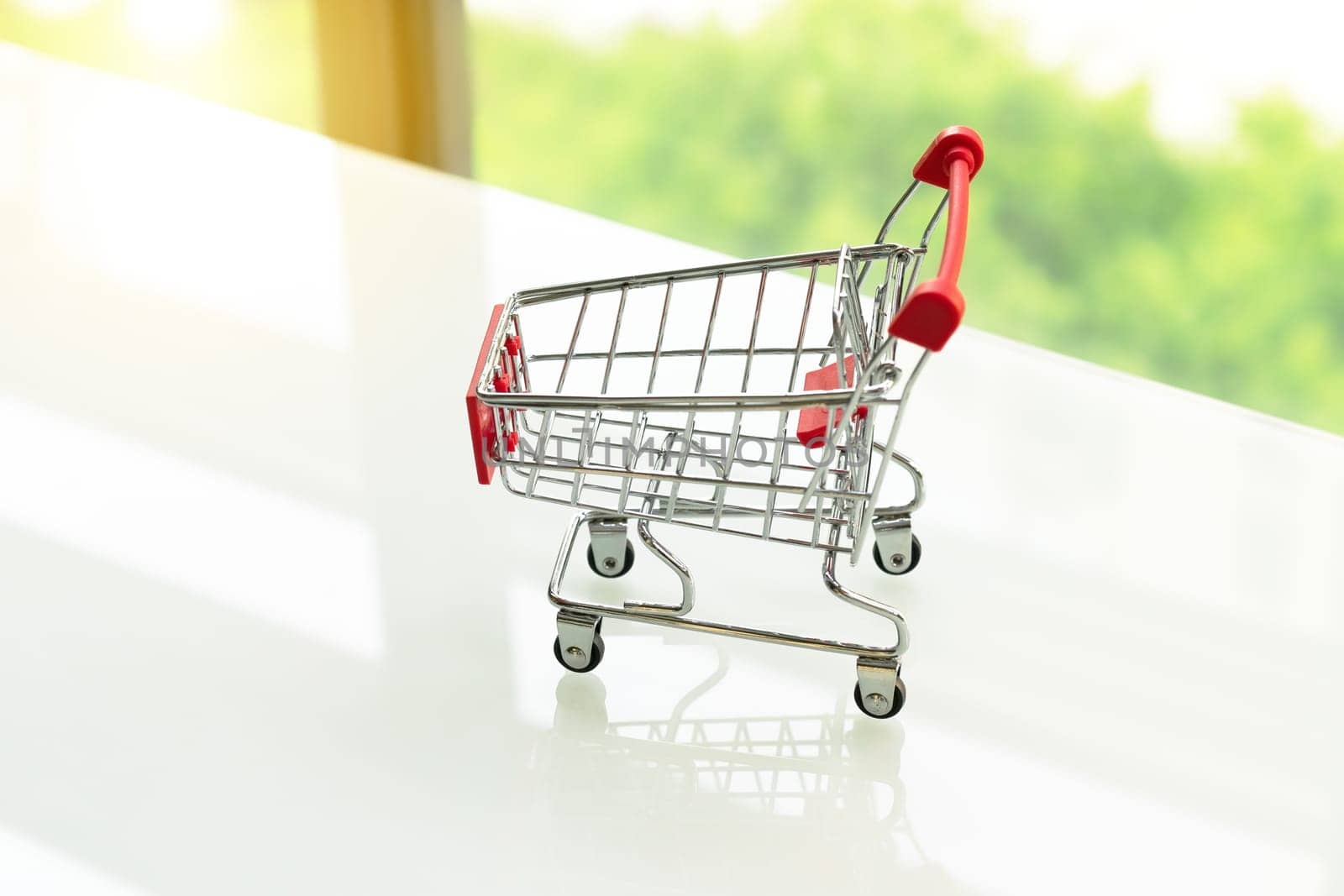 Empty shopping cart trolley on white table with green backgrounds