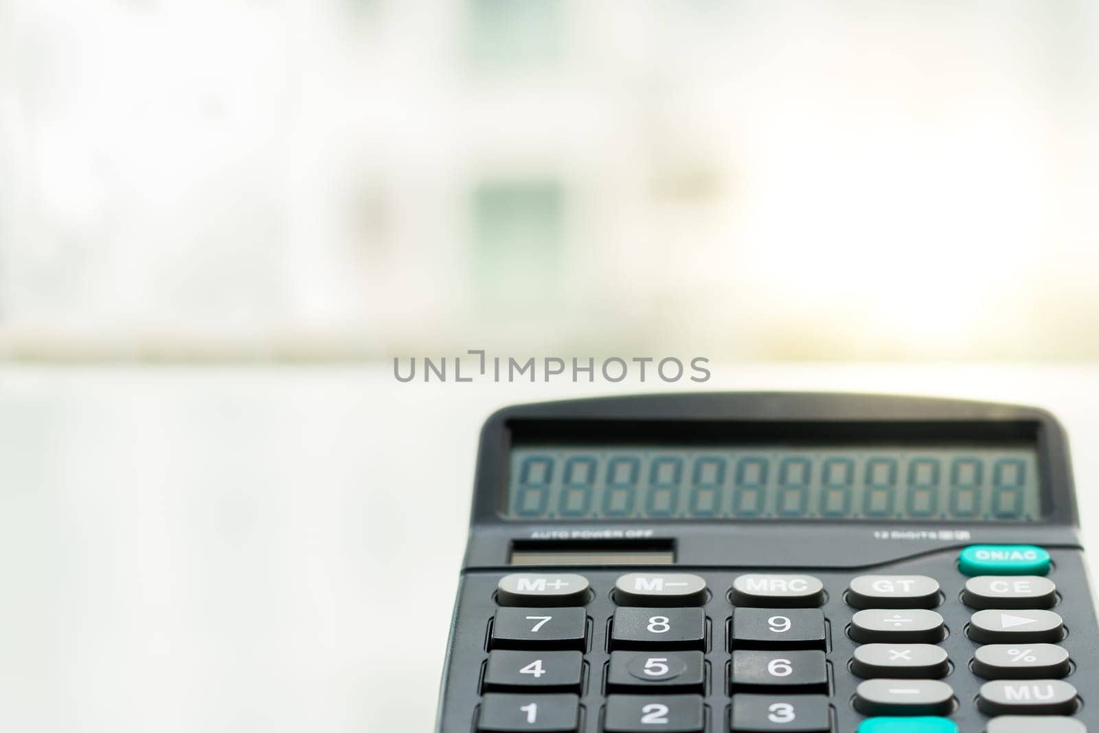 Calculator on the white table near window, closeup sideview isolated