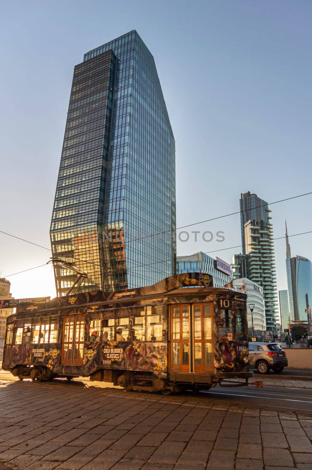 A tram travelling  in front of Modern buildings,  in the Business district in the city of Milan, Italy