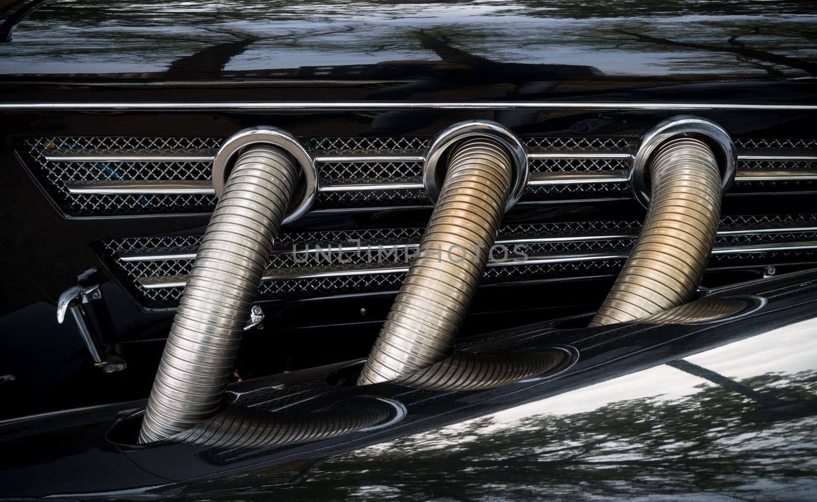 three chrome exhaust pipes on a black oldtimer car
