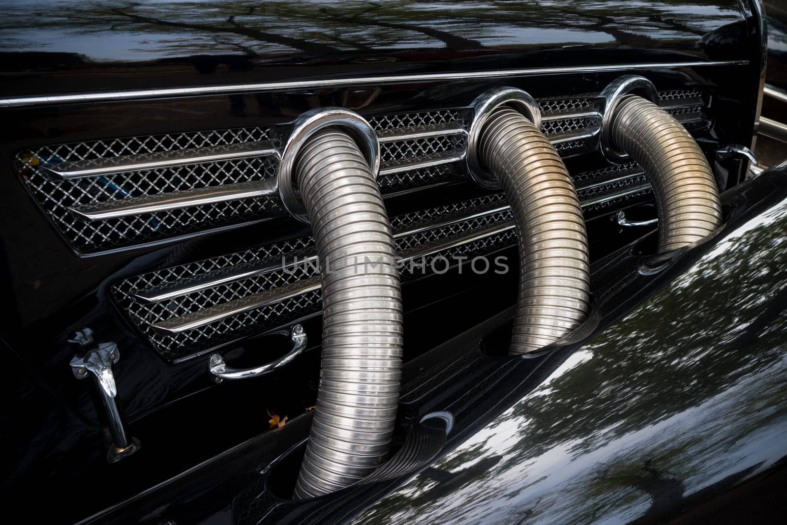 three chrome exhaust pipes on a black oldtimer car
