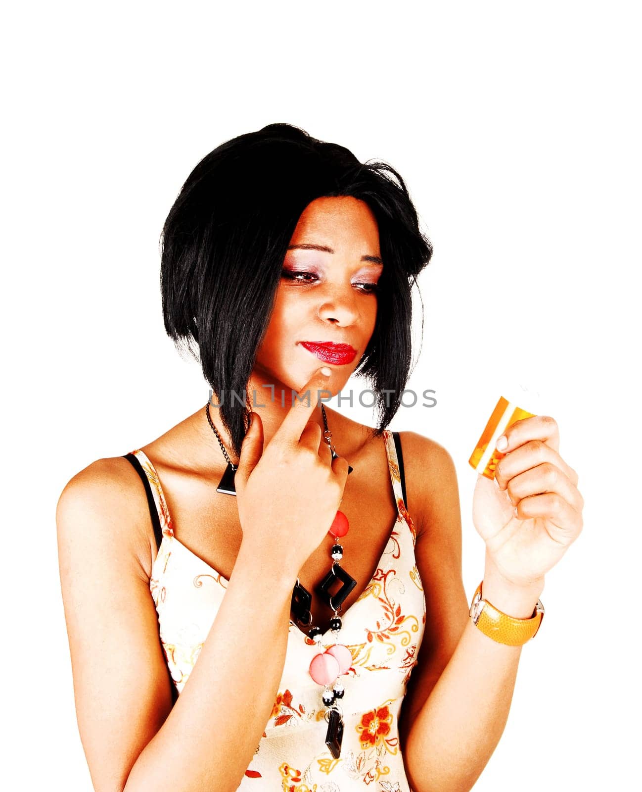 A young beautiful woman holding up some pills she is about to take.but hesitate, isolated for white background.
