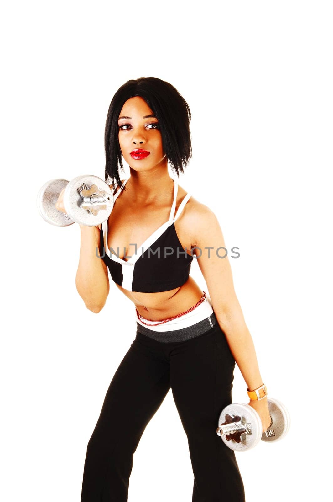 A young pretty woman standing in the studio, working out with two.dumbbells in her black sports outfit, isolated for white background.