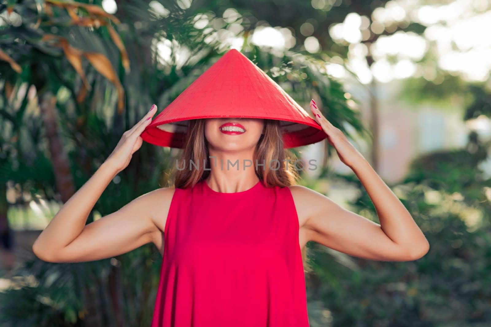 Fashion portrait of a beautiful woman in red conical hat outdoor
