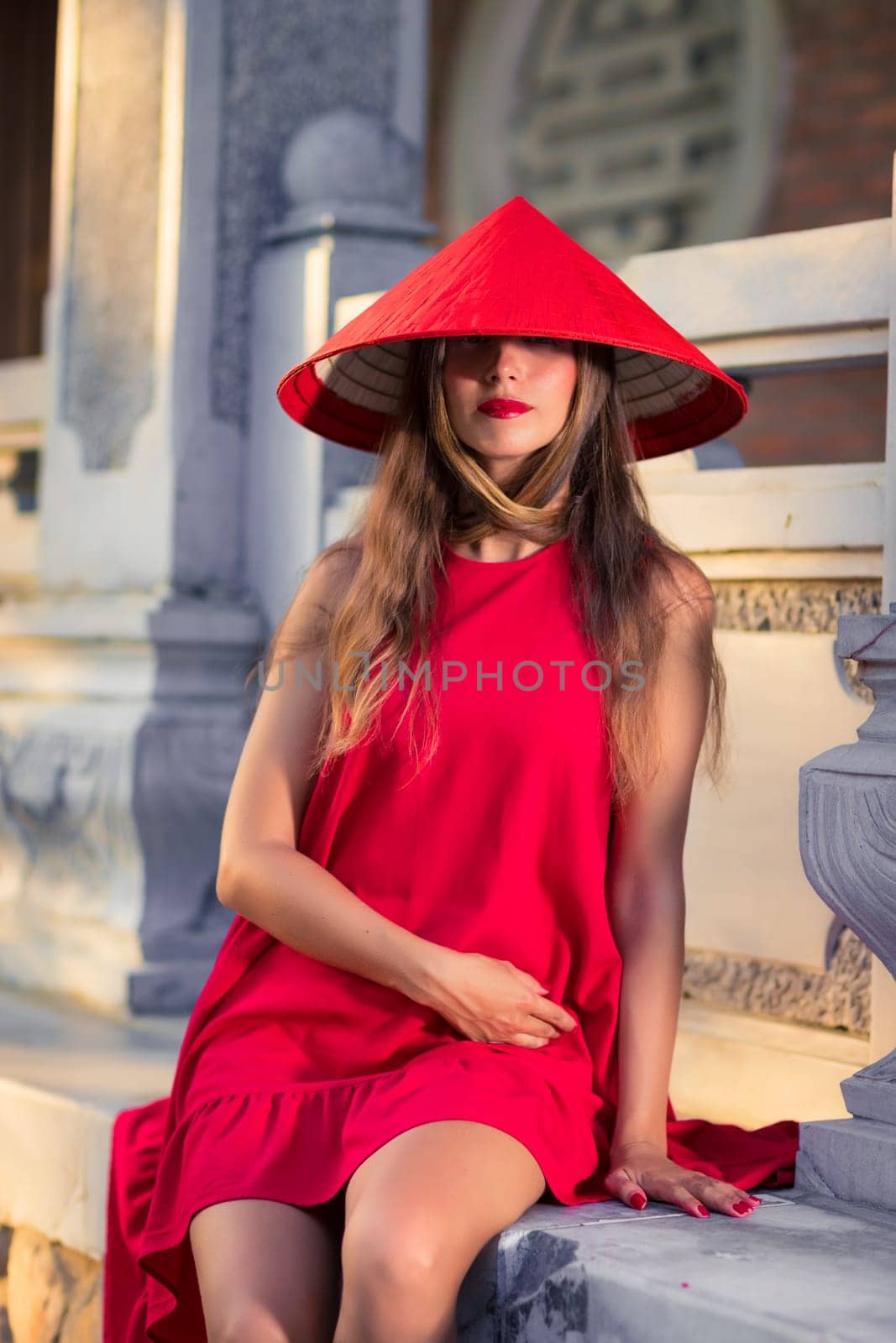 Fashion portrait of a beautiful woman in red conical hat outdoor