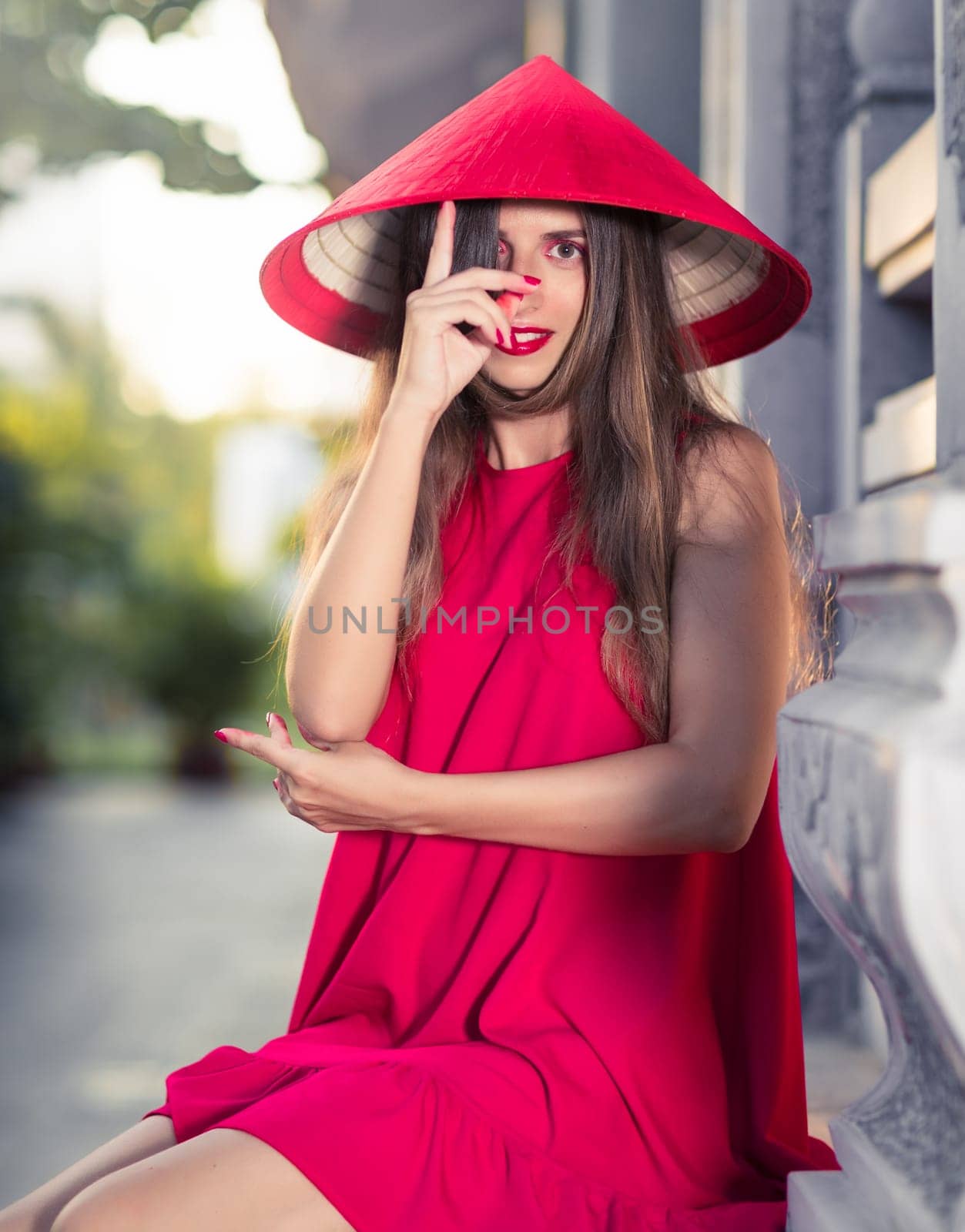 Fashion portrait of a beautiful woman in red conical hat outdoor