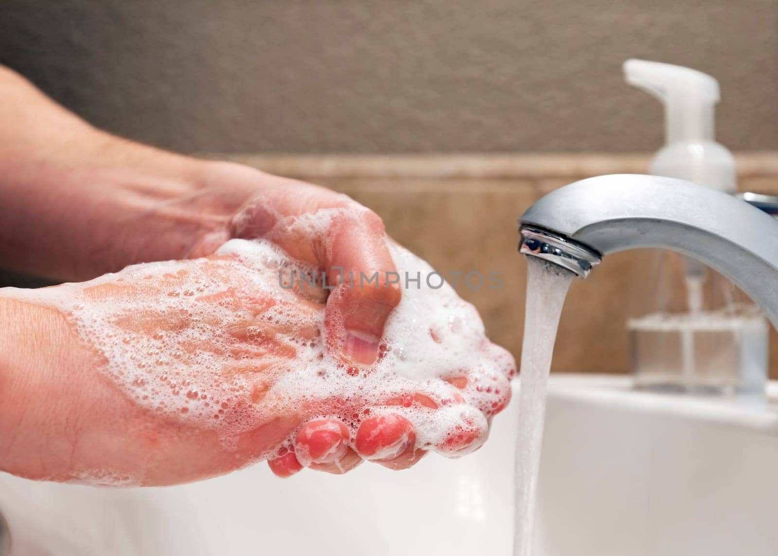 Washing hands with soap and water in bathroom sink, protection against viruses and bacteria, hygiene to stay healthy
