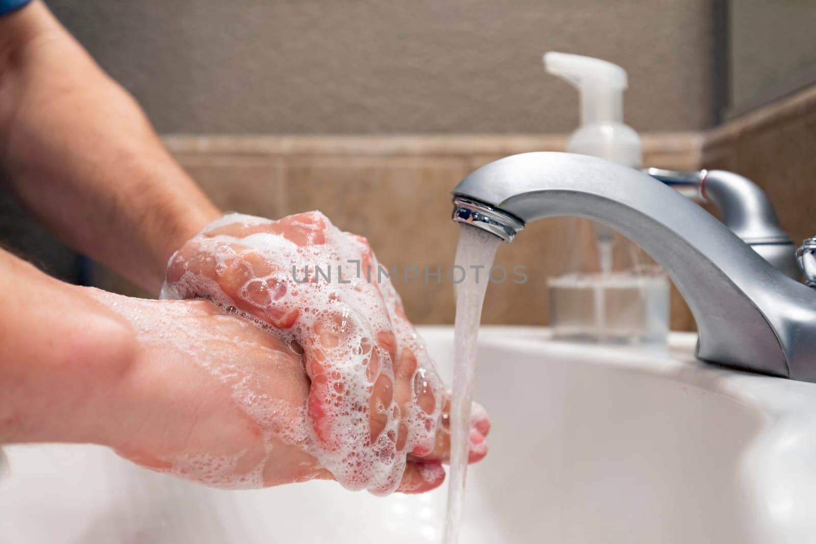 Washing hands with soap and water in bathroom sink, protection against viruses and bacteria, hygiene to stay healthy