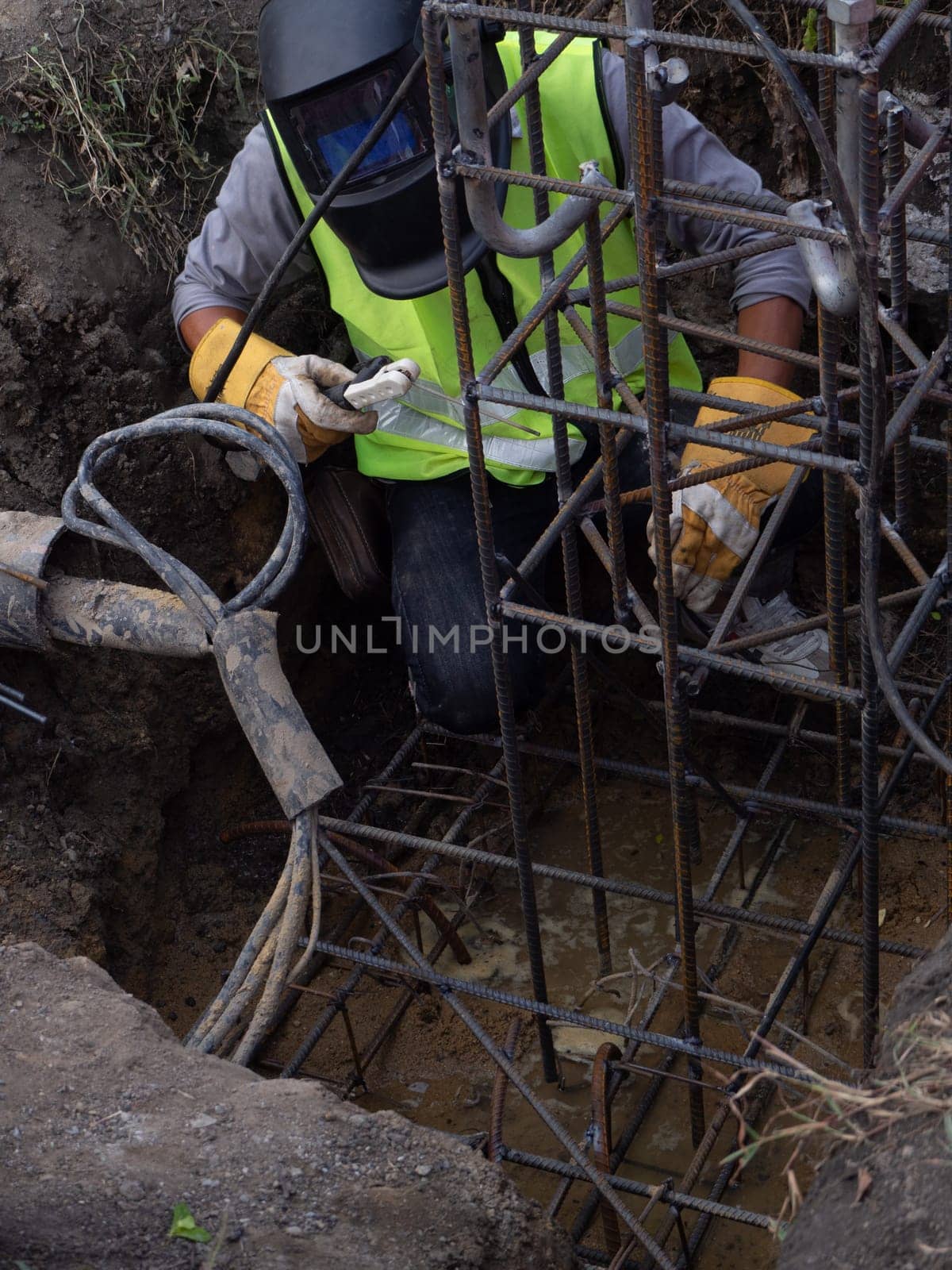 Worker in protective mask welding steel railings outdoors, sparks fly down