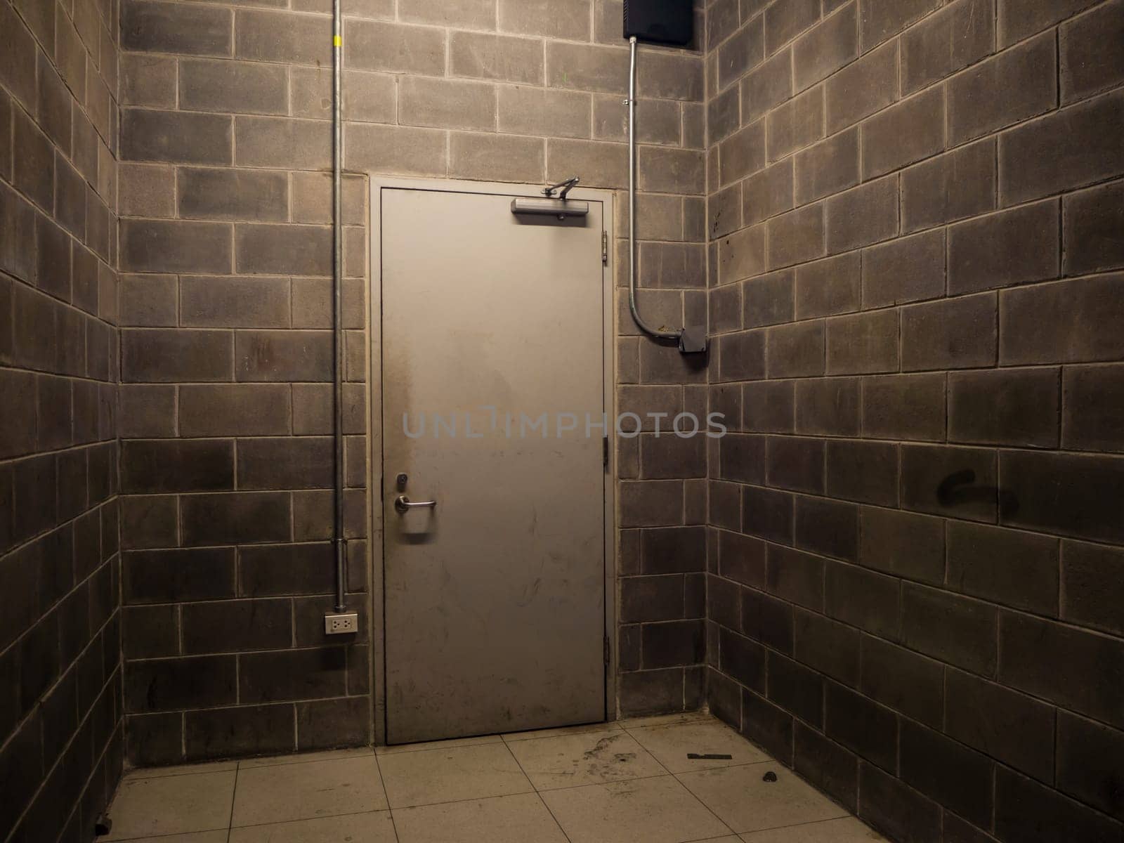 The metal Beige back door of building with old brick wall