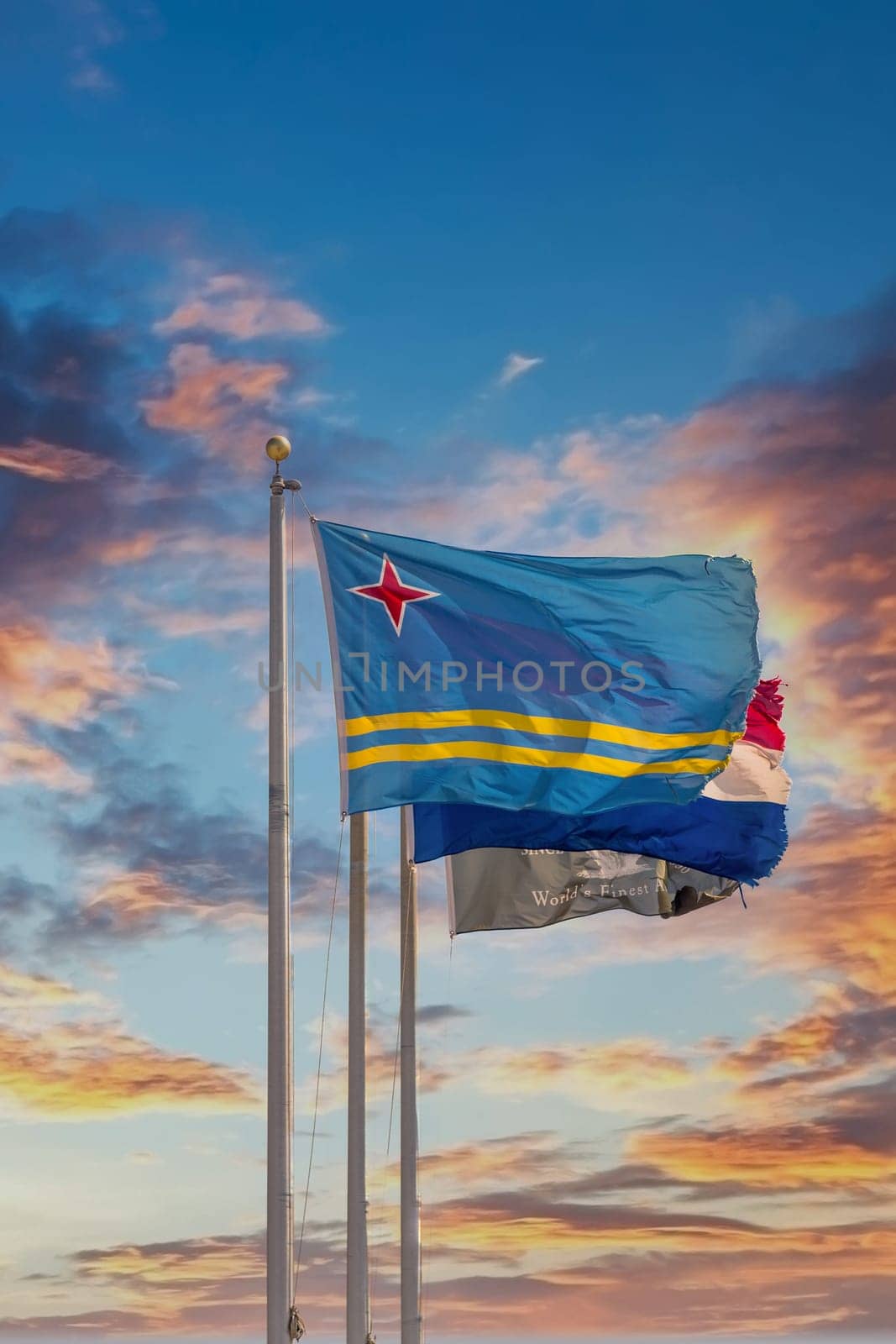Flag of Aruba on flagpole under blue skies
