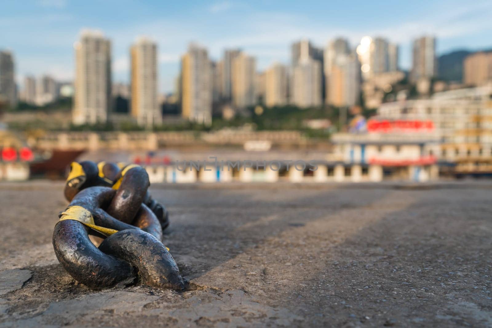 A closeup selective focus shot of a steel chain with a blurry background of buildings