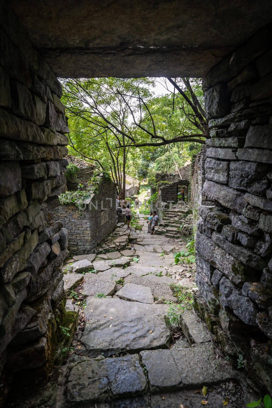 A vertical shot of people in a beautiful ancient landscape build with stones in a forest