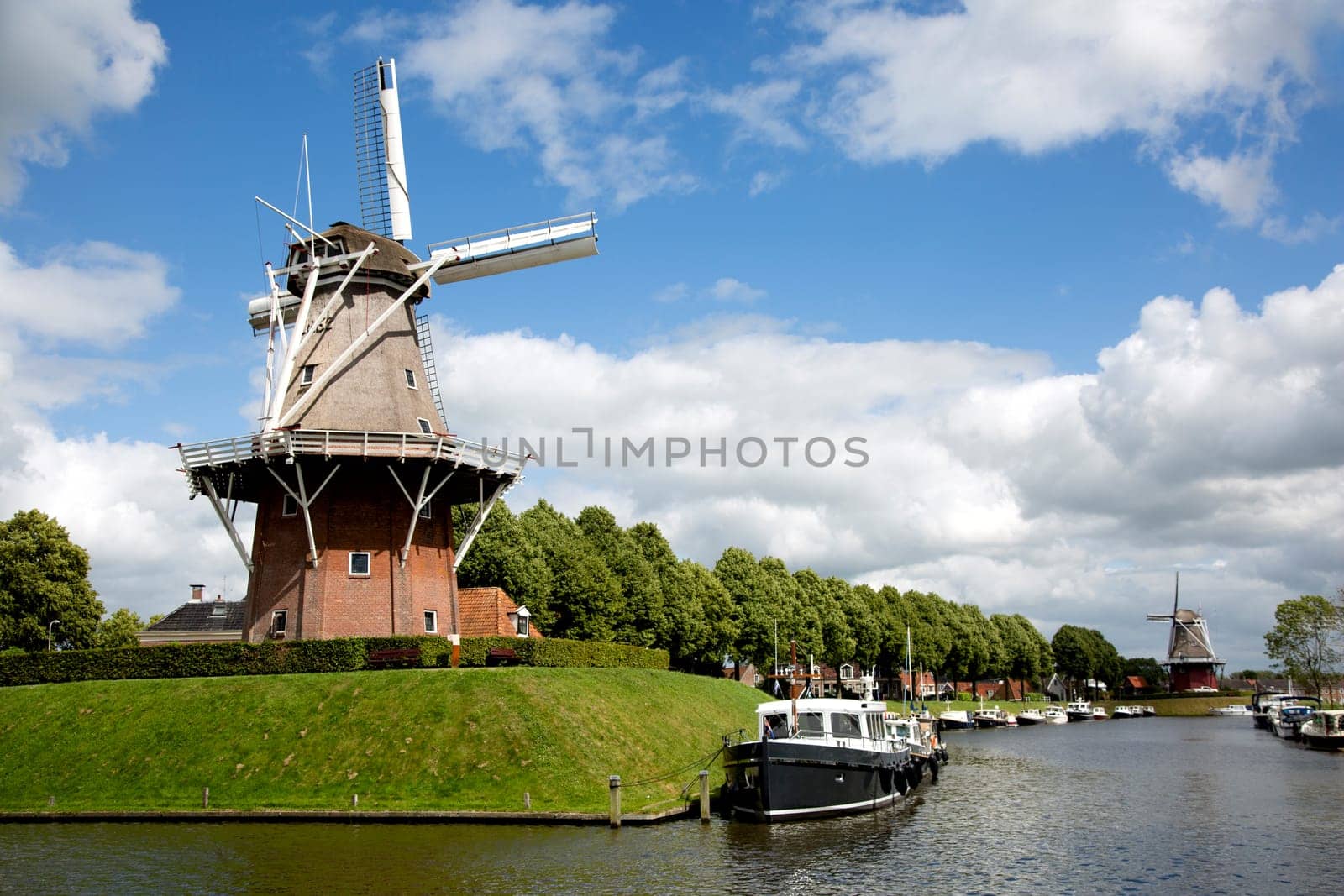 Dokkum, Friesland, The Netherlands - Jun 30, 2019  Boats on canal and windmill on fortifications of historic town Dokkum, Friesland, The Netherlands..
