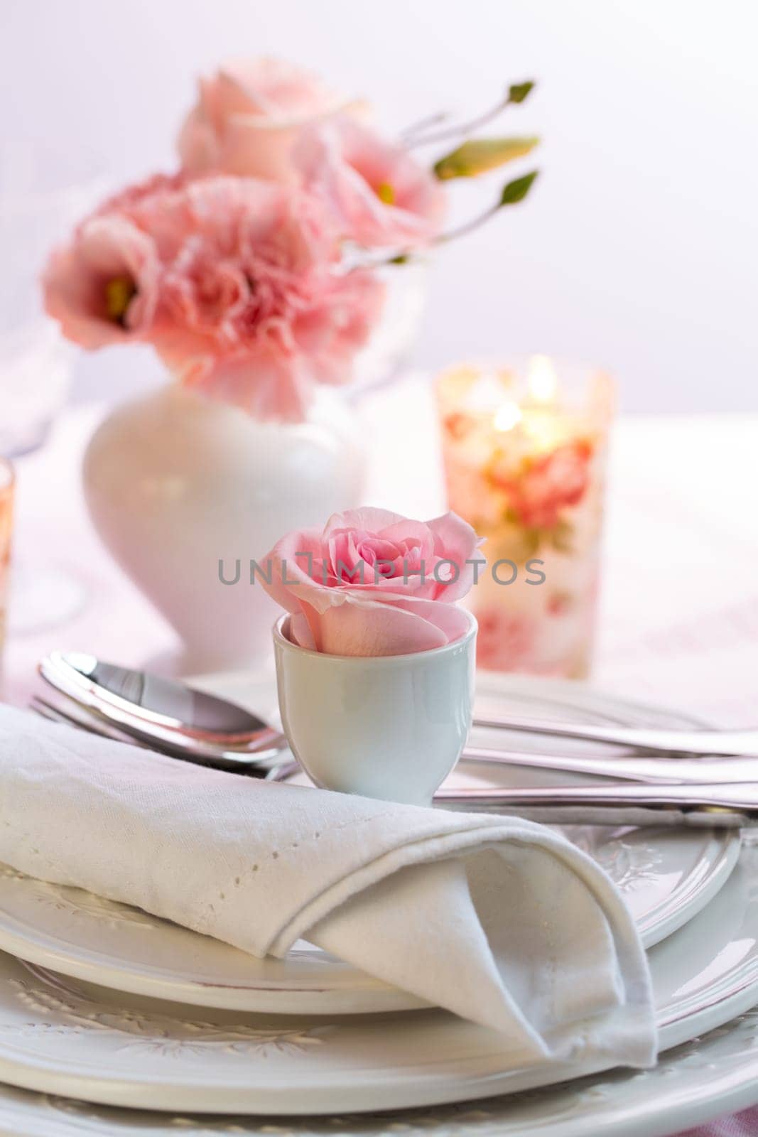 Place setting with beautiful bouquet in vase in pink and white on the kitchen table