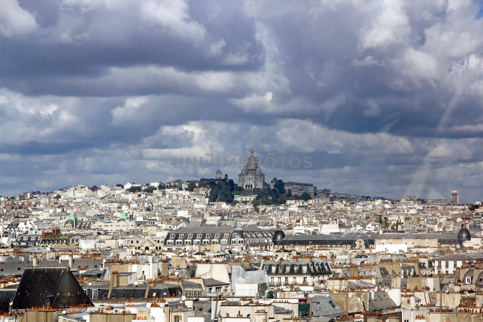 The roofs of Paris under a stormy sky. In the distance the Sacré Coeur Paris France