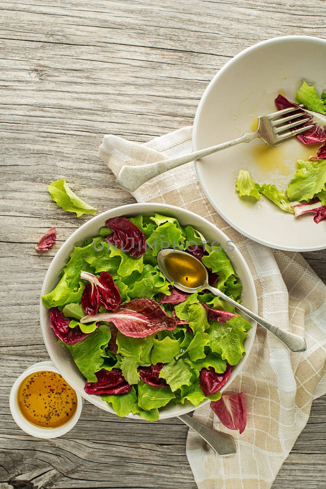 Healthy red and green lettuce salad meal on wooden table background. Eating fresh radicchio and young lettuce with dressing sauce