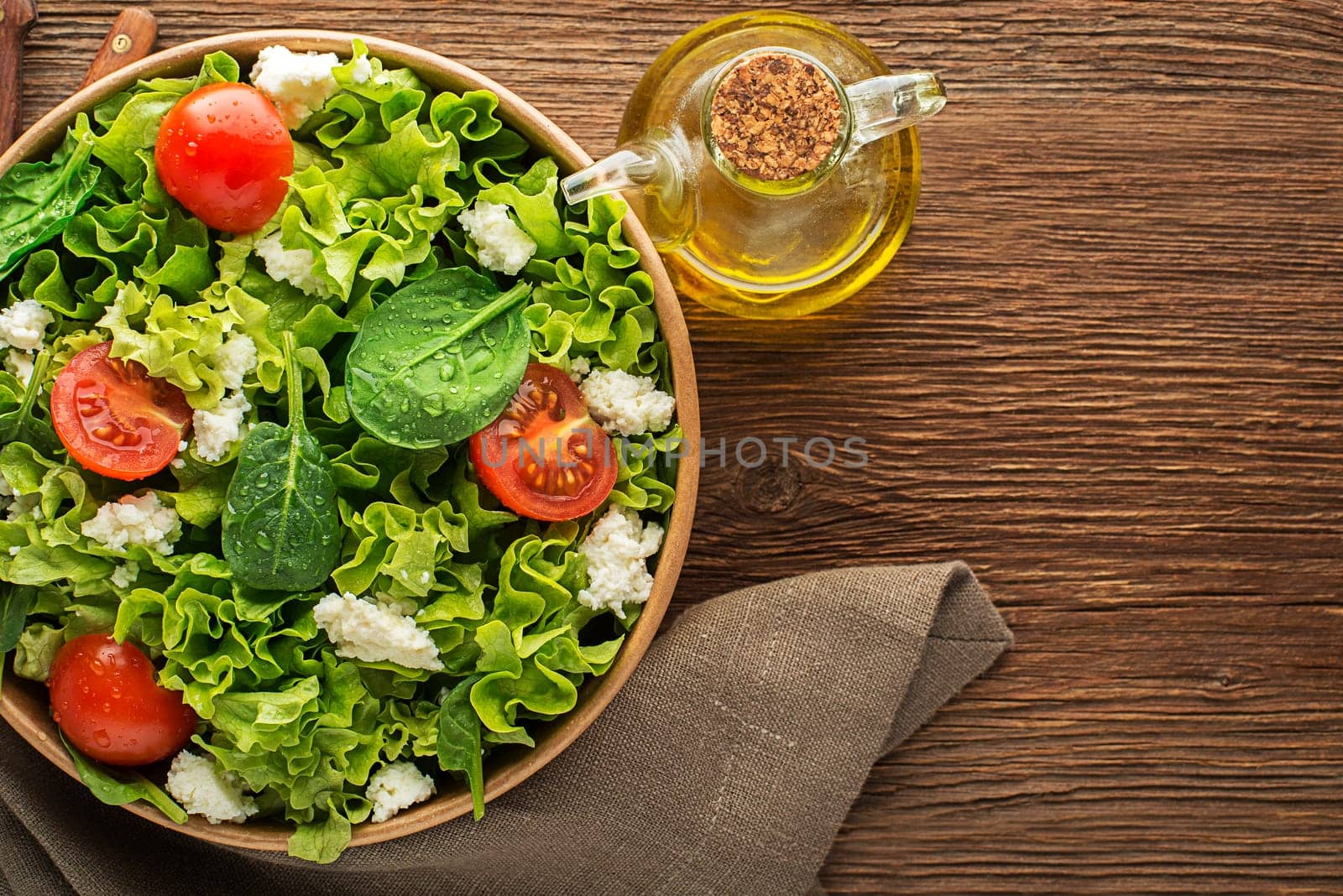 Healthy Green salad with fresh tomato and fresh cheese on wooden background close up