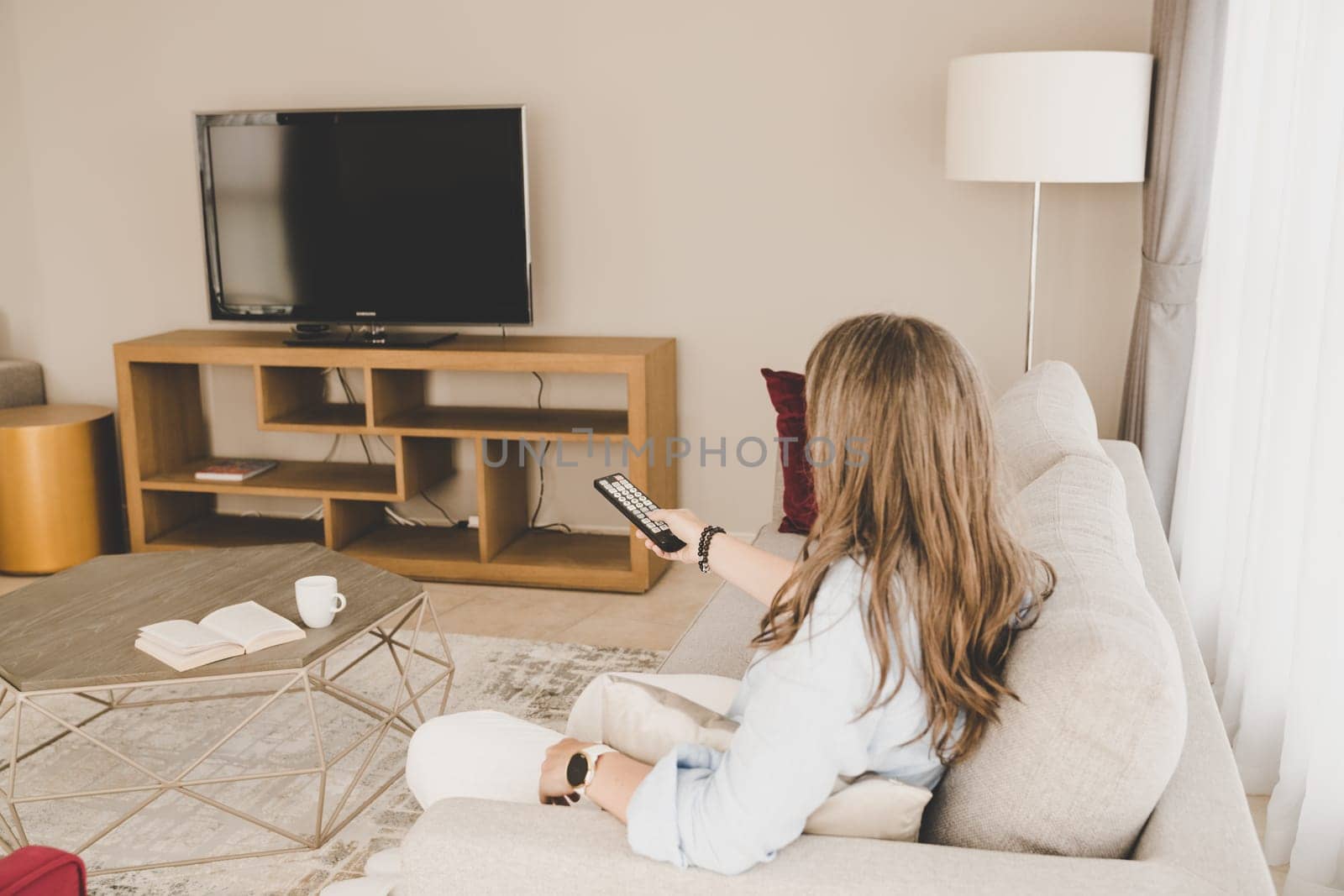 A woman on a sofa getting ready to watch TV