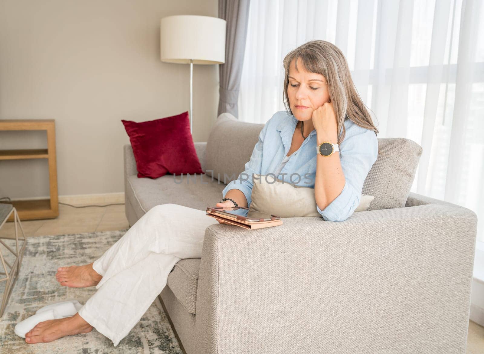 Mature woman looking at a tablet screen in her urban apartment