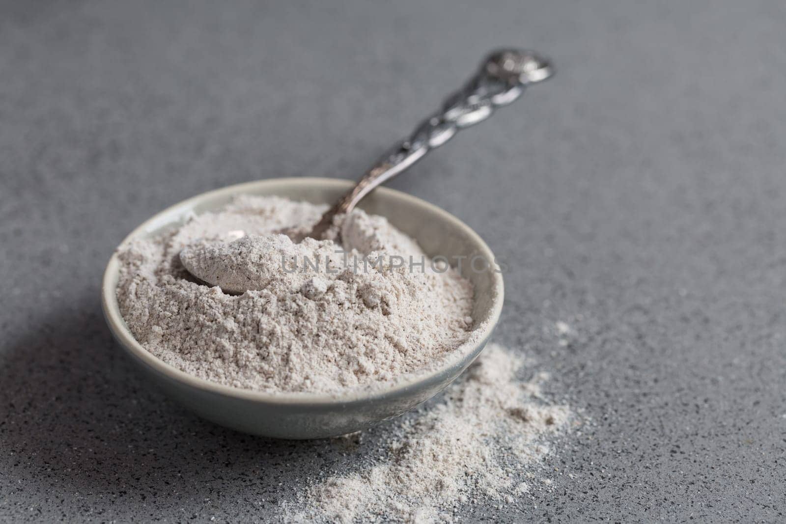 Glutenfree buckwheat flour for baking in the bowl on grey background