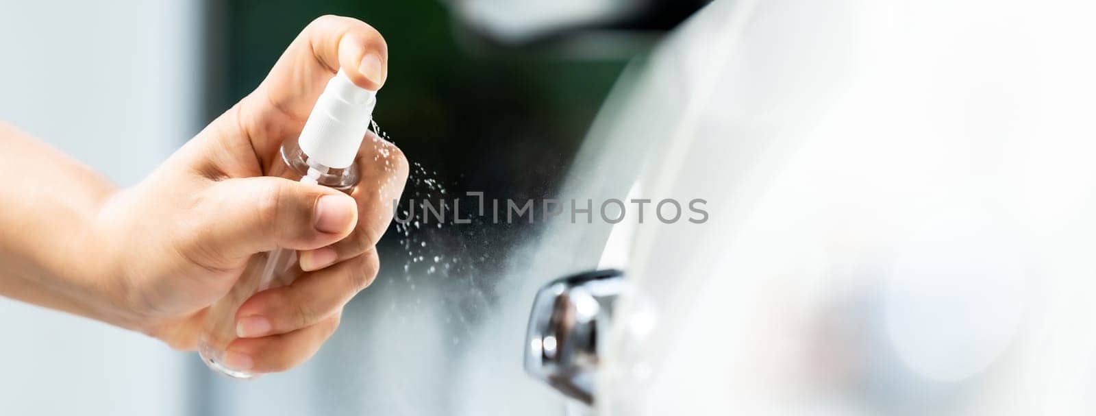 panoramic web banner,  car cleaning using hand spraying alcohol, disinfectant spray on car door handle for safety prevent and protect from infection of virus and germ Covid-19 coronavirus pandemic.