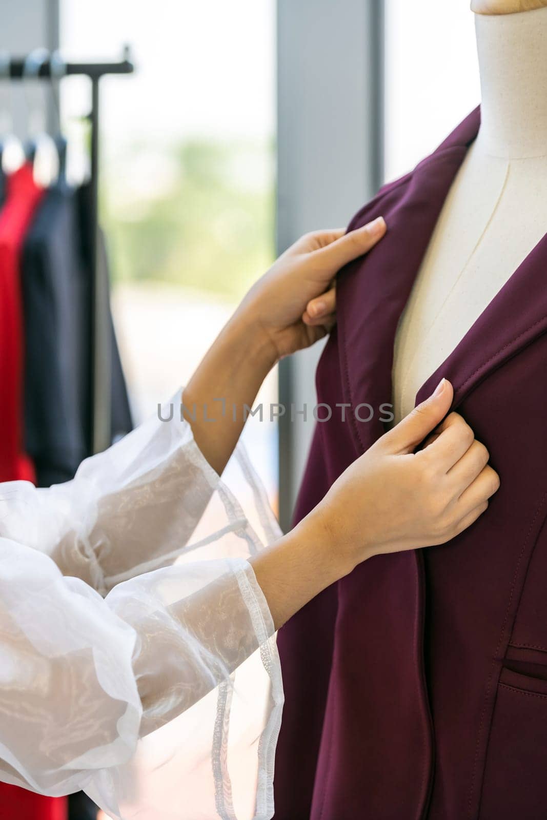 Close-up young adult asian fashion designer checking at suit arm on mannequin at her atelier studio as before deliver to her customer. For entrepreneur small business startup work from home concept.