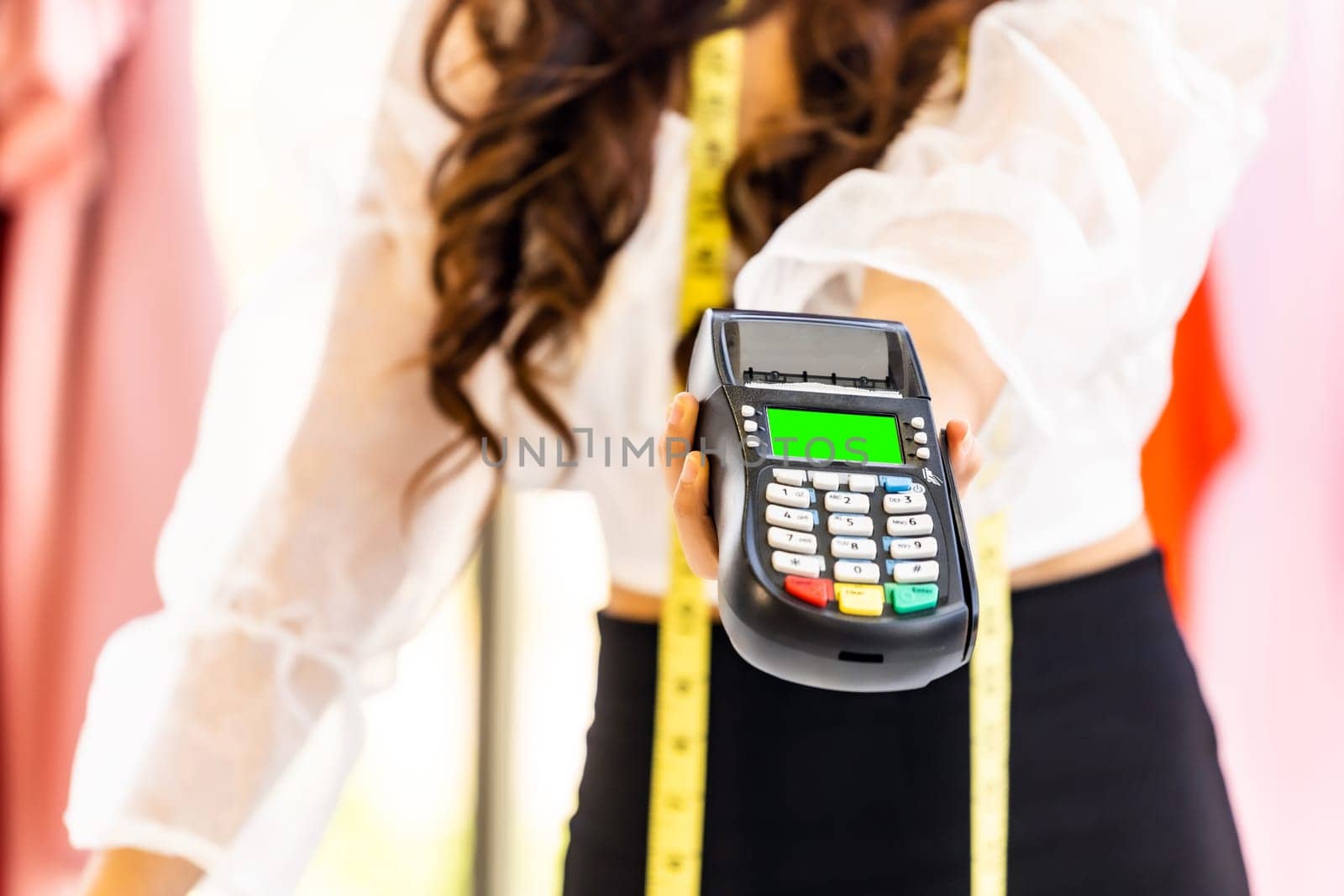 Close-up fashion designer hand hold EDC Machine for customer payment with credit card at her atelier studio as sole owner. Using for entrepreneur startup and consumerism concept.