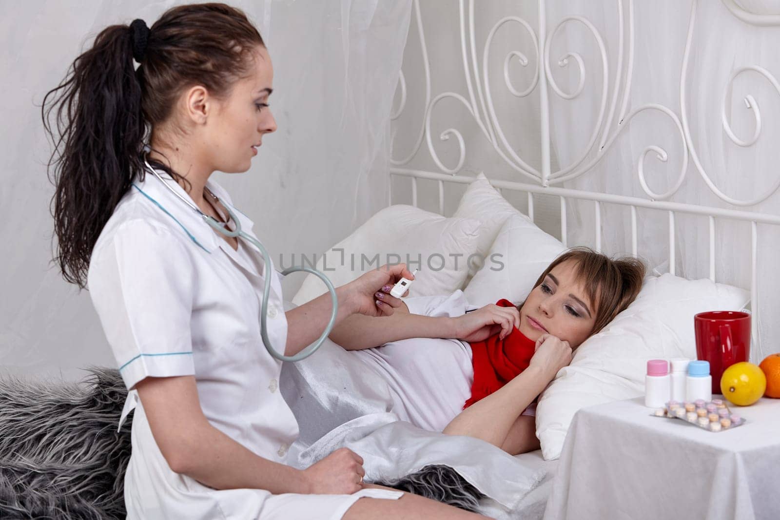 The doctor examines the ill girl lying in a bed. Selective focus.