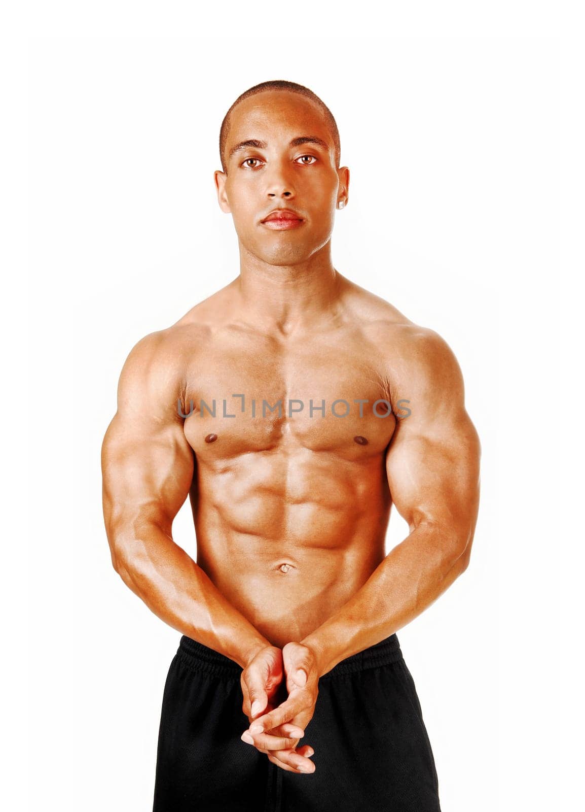 A young man standing in the studio with his hands folded showing his.great physique and muscles, isolated for white background.