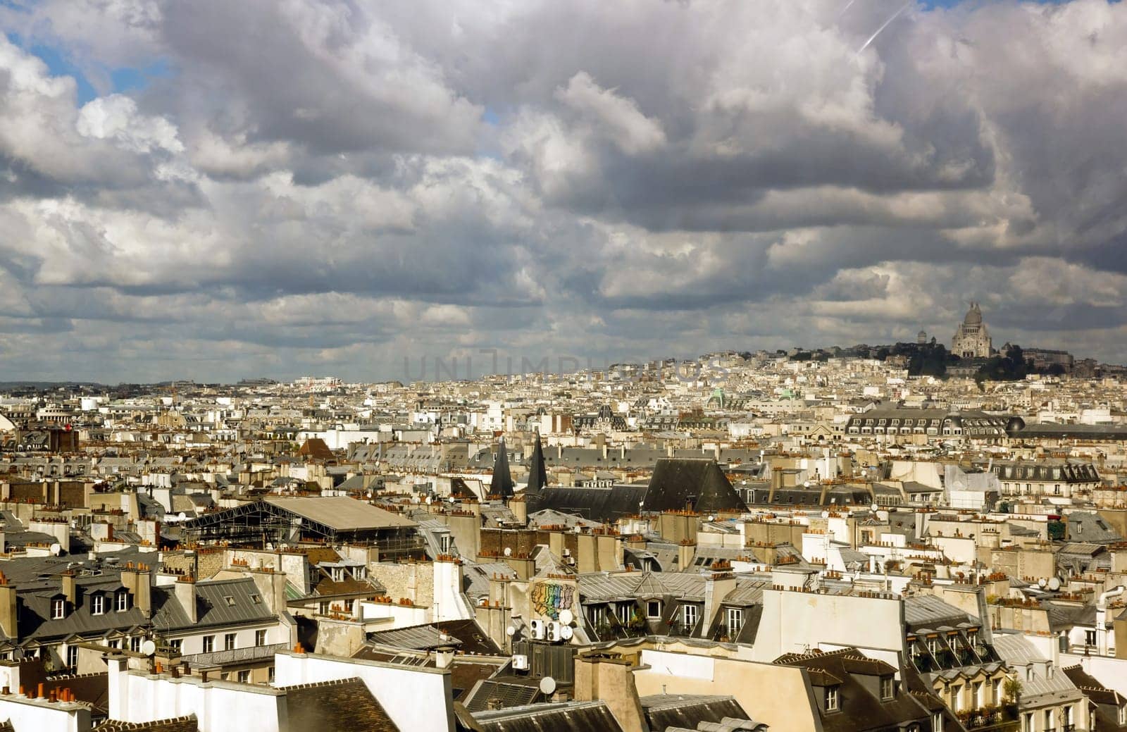 The roofs of Paris under a stormy sky. In the distance the Sacre Coeur (Paris France)