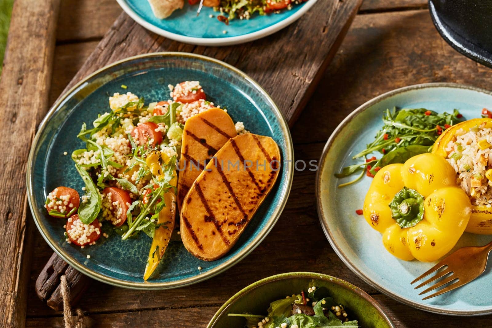 A close up of various gourmet vegetarian dishes on a rustic timber table.