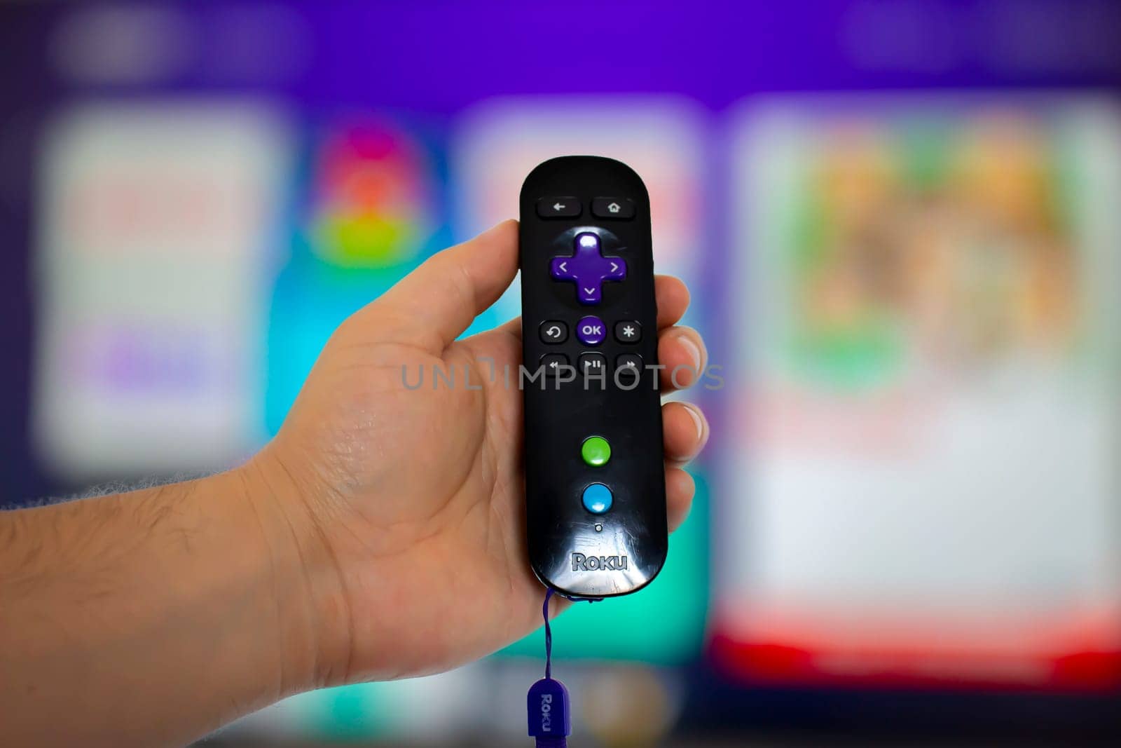 Calgary Alberta, Canada. May 5, 2020. A person holding a Roku remote control with a screen tv on the background