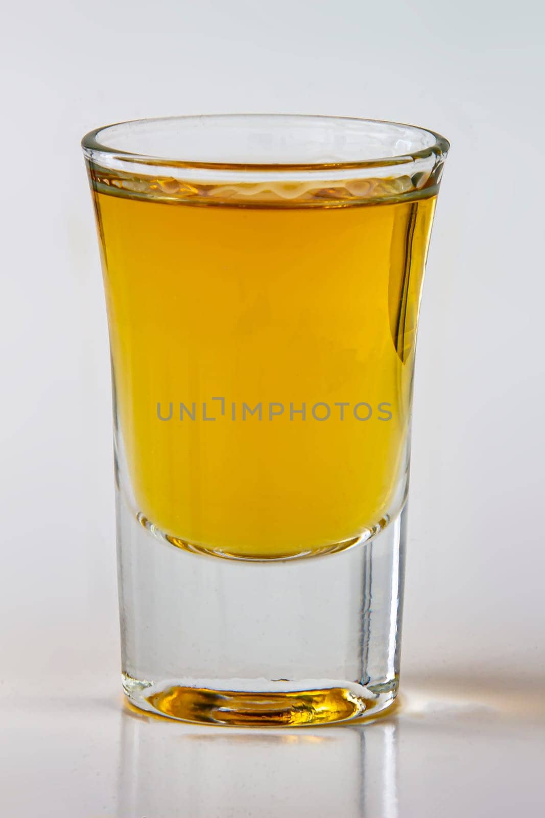 Close up vertical view of a liquor shot drink on a white background