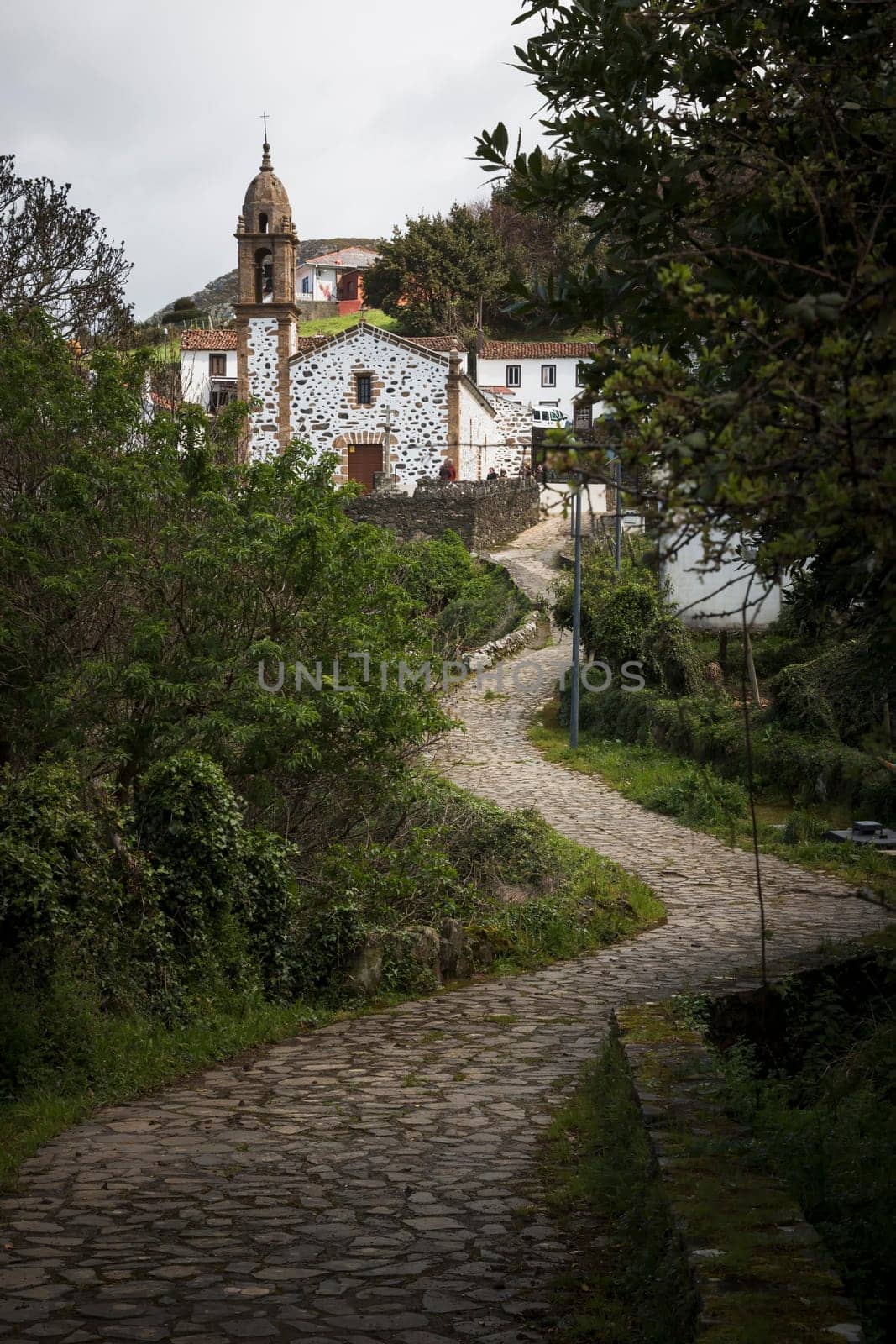 San Andres de Teixido, Spain - 01, 04, 2017: A winding, cobbled path leads to the chapel of San Andres de Teixido between trees and vegetation
