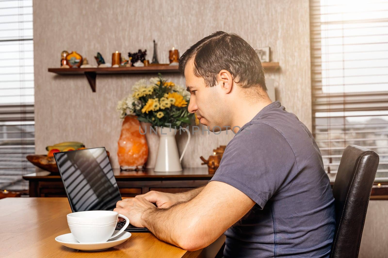Middle age man working on document on the laptop from comfort of his home at sunny day during covid 19 or coronavirus pandemics and quarantine