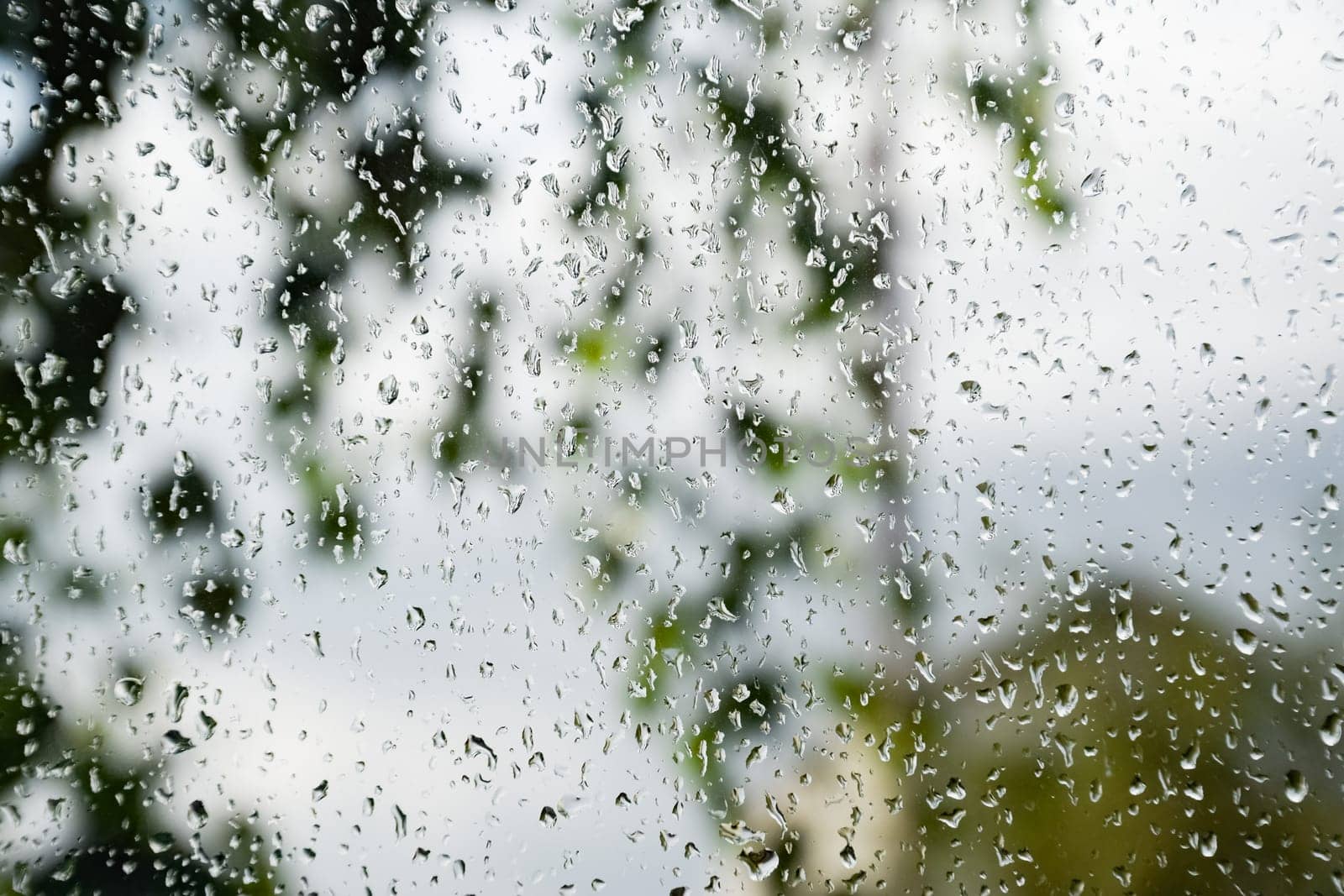 Raindrops on the window pane. Blurred background outside the window in the rain.