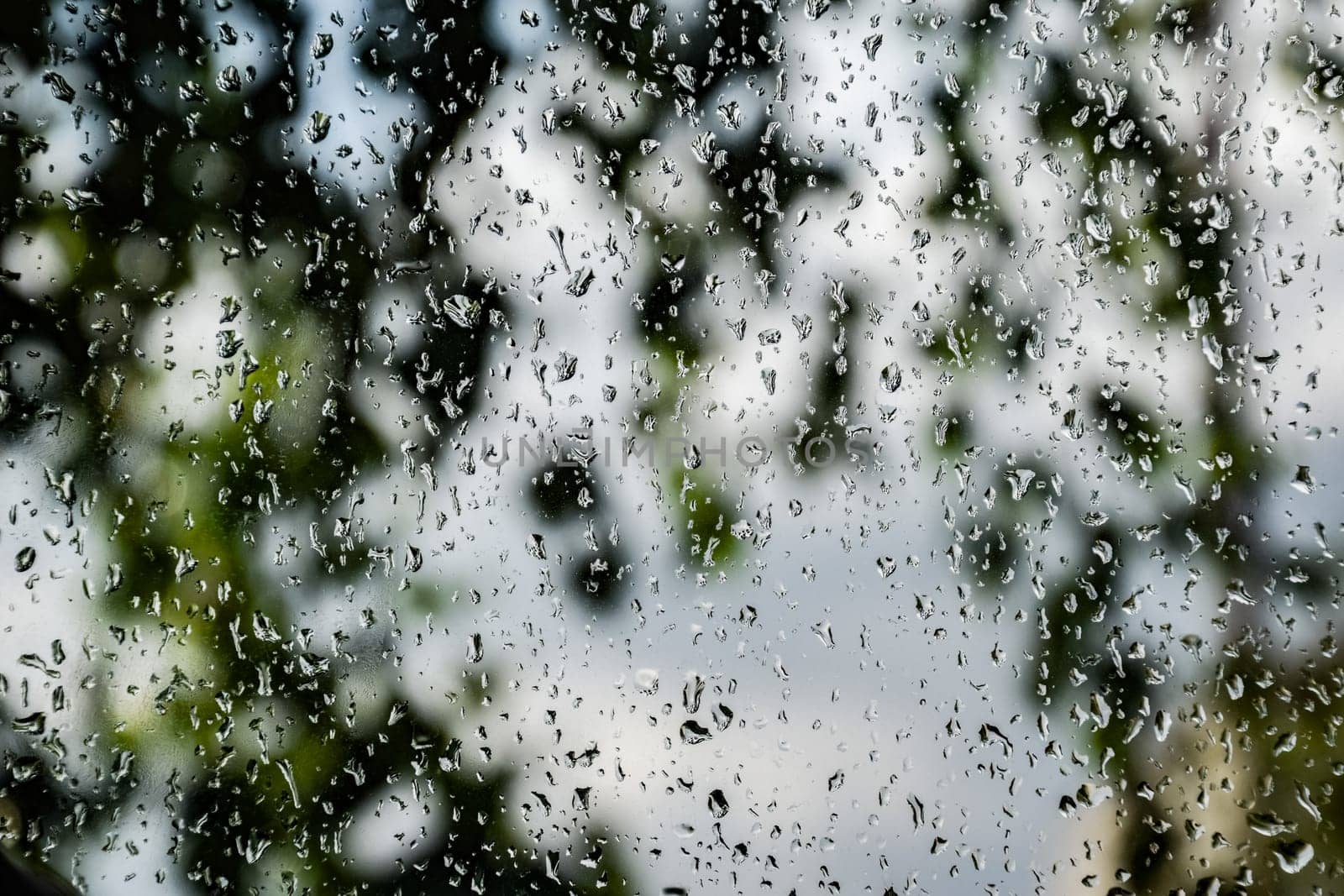 Raindrops on the window pane. Blurred background outside the window in the rain.