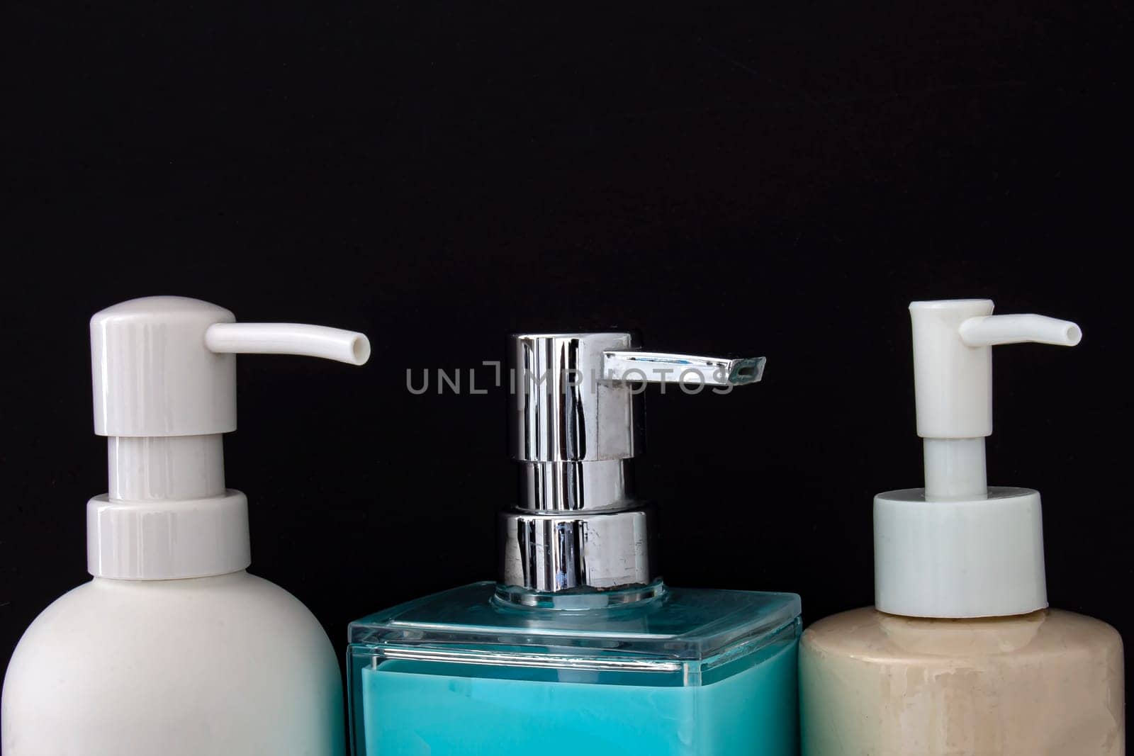 Close up top view of colorful soap dispenser for bathrooms or kitchen sinks on a black background