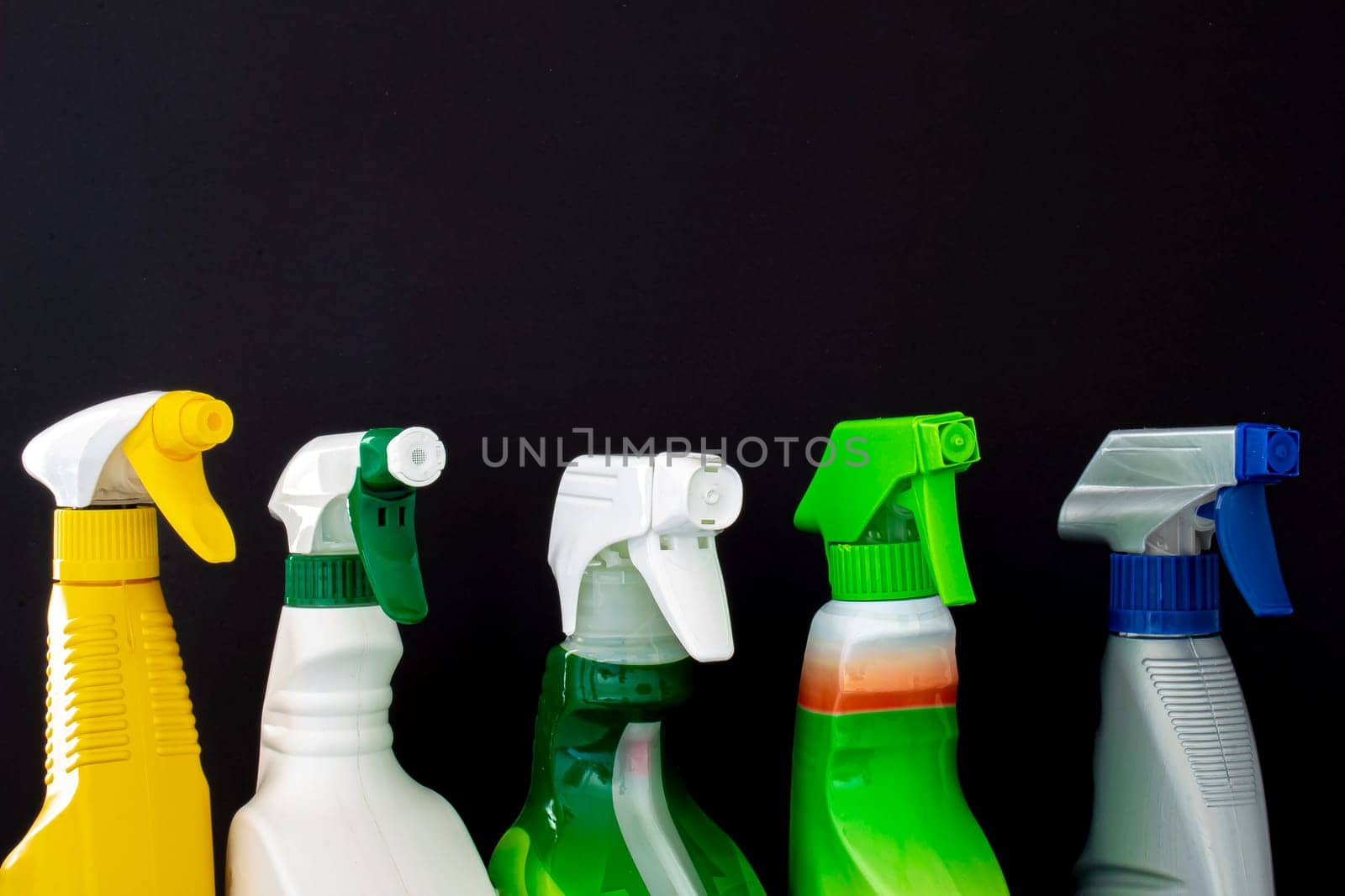 A group of colorful spray cleaners bottles on a black background
