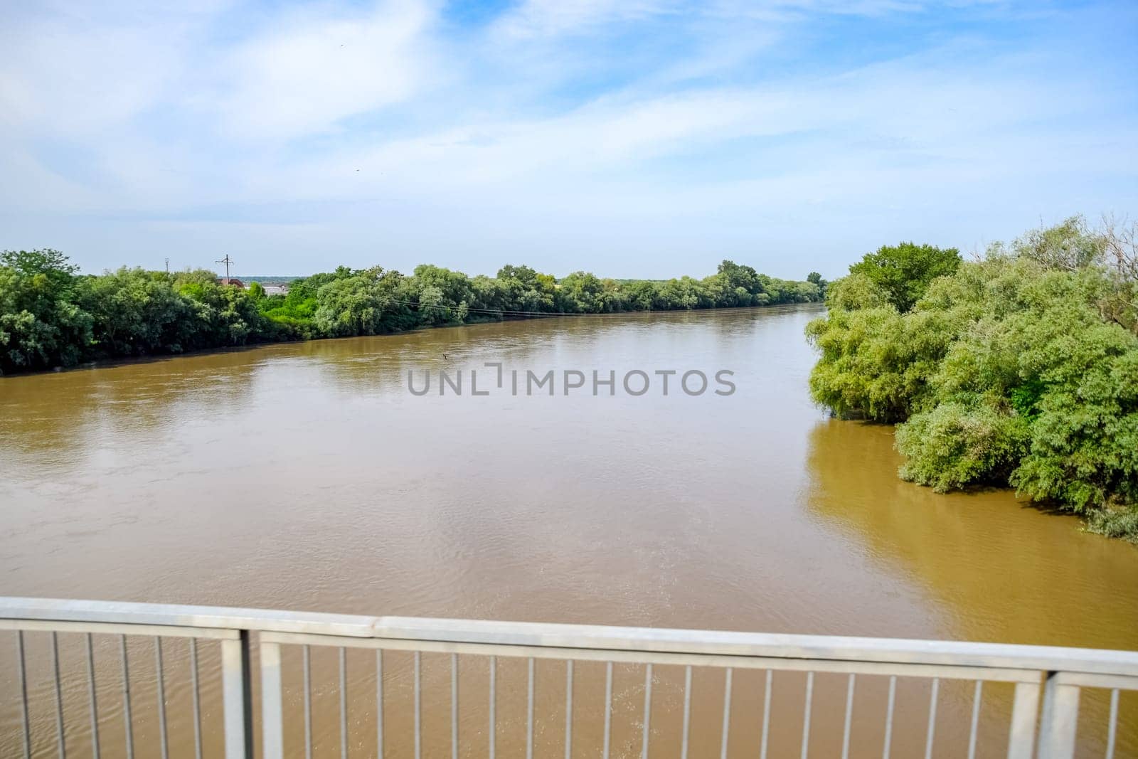 Passing over the bridge over the river. The landscape of the river, the surface and the trees of the river's waterplain.