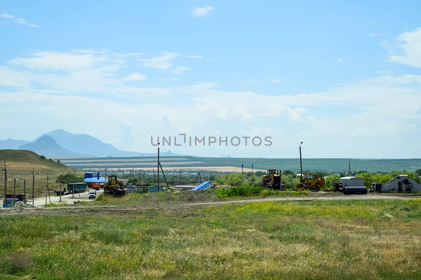 Old agricultural machinery stands in a village on a site with agricultural machinery
