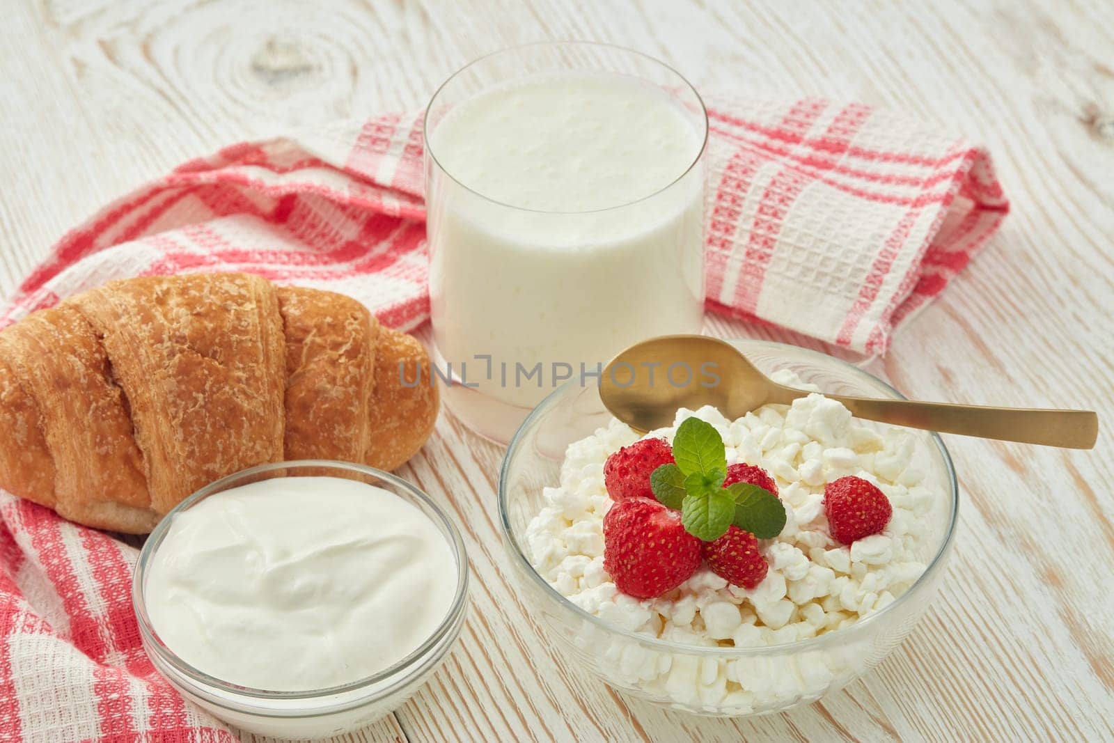 Still life with natural cottage cheese with fresh ripe strawberries and leaf of mint, sour cream, yogurt and croissant. Healthy food. Dairy producst. Dietary product.